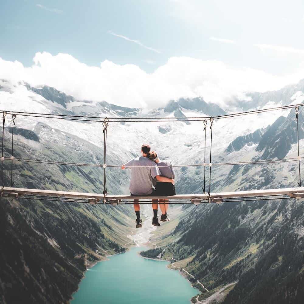 a couple sitting on a hanging bridge - adventurous activity for one year anniversary